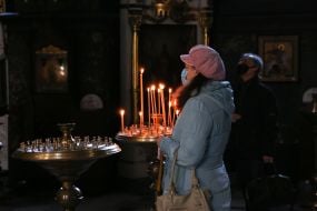 Прихожанка в медицинской маске стоит возле иконы во Владимирском кафедральном соборе