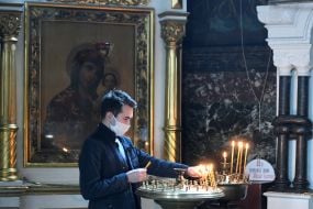 The clergyman removes candles from the candlestick in the Vladimir Cathedral
