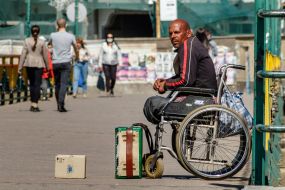A Roma man on a wheelchair is begging