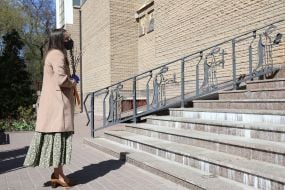 Прихожанка в медицинской маске с веточками ивы в руках стоит у храма Святого Василия Великого