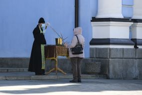 The clergyman sprinkles a willow branch with holy water