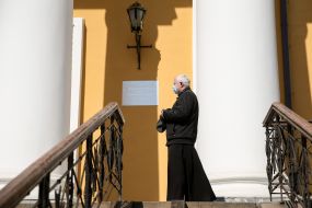 The priest in a medical mask in front of the temple