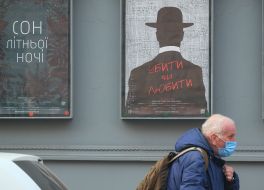 Мужчина в медицинской маске проходит возле здания театра