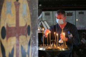 Верующий ставит свечу на подсвечник