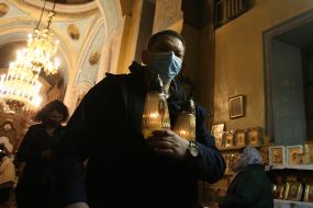 The priest is carrying a lamp with the Holy Bless