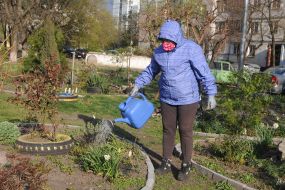 Woman in medical mask watering flowers