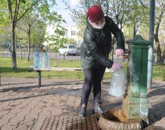 A woman in a medical mask collects water