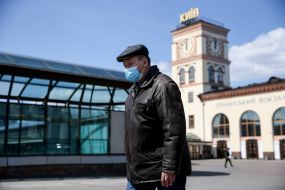 Чоловік у медичній масці біля будівлі приміського вокзалу