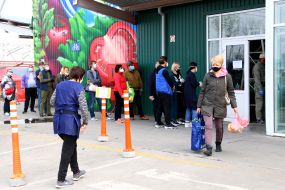 People are waiting in line at the entrance to the market