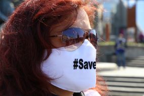 Participant of peaceful protest action "SaveFOP" in a medical mask with the inscription "#Save" on Independence Square