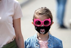 Little girl in medical mask and pink sunglasses