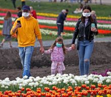 Man, woman and girl in medical masks at the Dobropark Arboretum