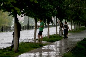 Перехожі ховаються від дощу під деревами