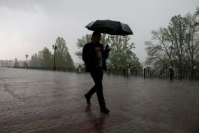 Чоловік з парасолькою йде під дощем