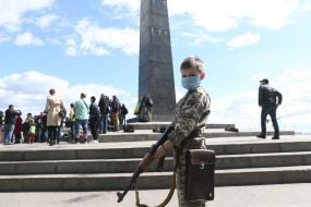 Мальчик в медицинской маске и камуфляже с оружием в руках