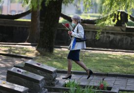 A woman carries flowers on the territory of the Hill of Glory memorial complex