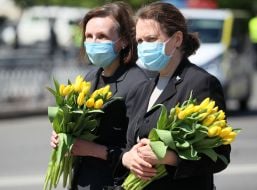 Женщины в медицинских масках держат тюльпаны в руках