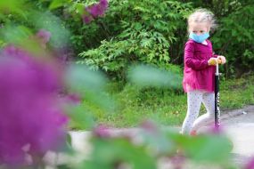 Girl in a medical mask on a scooter in the Kyiv Botanical Garden named after Grishko