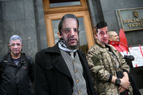 Masked activists with portraits of Andriy Yermak and Volodymyr Zelensky