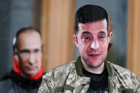 An activist in a mask with a portrait of Volodymyr Zelensky