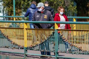 Люди в защитных масках идут по пешеходному мосту