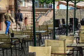 Люди проходят у пустых террас ресторанов