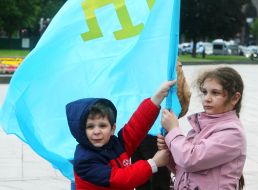 A boy and a girl hold the flag of the Crimean Tatars