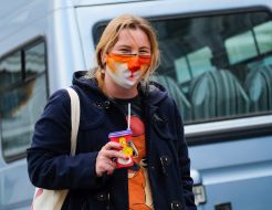 Woman in a medical mask with a paper cup of coffee in her hands