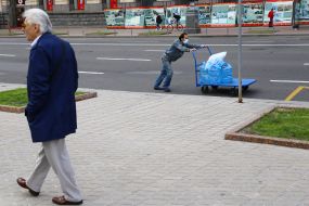 A man in a medical mask carries water in a wheelchair