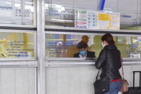A woman in a mask buys a ticket