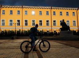 A man on a bicycle near the monument to Mykhailo Hrushevsky