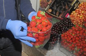 The seller holds a container with strawberries
