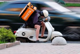Courier of RAKETA delivery service on a moped