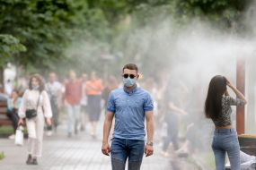 Перехожі проходять біля охолоджувальних рамок, які розбризкують водяний пил