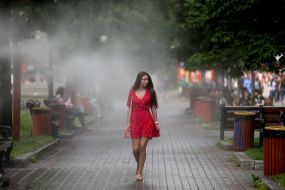 Дівчина проходить біля охолоджувальних рамок, які розбризкують водяний пил