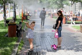 Дівчинка ловить бризки води біля охолоджувальних рамок, які розбризкують водяний пил