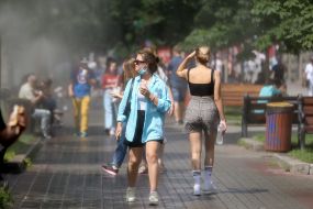 Перехожі проходять біля охолоджувальних рамок, які розбризкують водяний пил