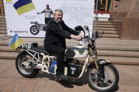 Чоловік фотографується біля електричного мотоцикла Dnepr Electric