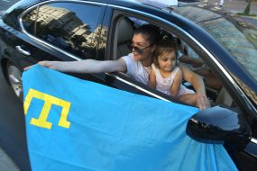 The girl holds the flag of the Crimean Tatars