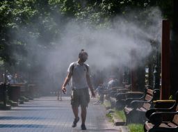 Мужчина в маске возле рамки с распылителями воды