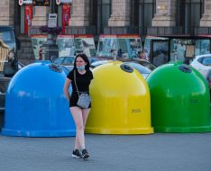 Girl in a protective mask near garbage containers