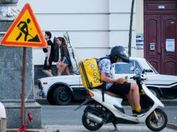 Young people with musical instruments and Glovo delivery courier on a moped