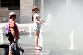 Дівчинка стоїть біля фонтану