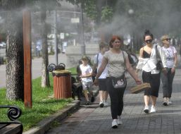 Passers-by pass by the cooling frames, which spray water dust