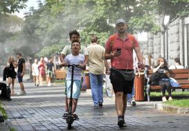 Passers-by pass by the cooling frames, which spray water dust