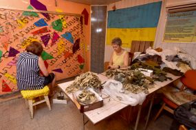Volunteers weave camouflage suits and nets for the army