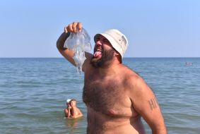 Чоловік тримає медузу в руках на пляжі в Бердянську