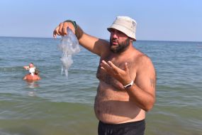 Чоловік тримає медузу в руках на пляжі в Бердянську