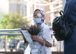 An elderly woman sells flowers on the street