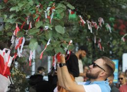 Activists hang white and red ribbons on trees